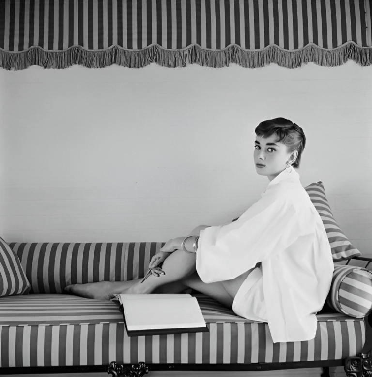Audrey Hepburn sitting gracefully on a sofa, representing elegant feminine presence in timeless fashion.